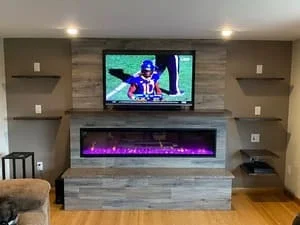 Wood-look tile accent wall with electric fireplace, floating shelves, and mounted TV