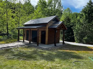 Modern cabin with board-and-batten siding, metal roof, and front porch in wooded setting