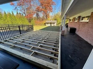 Composite deck framing with aluminum railings and pressure-treated joists under construction