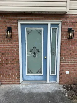Blue entry door with sidelite and frosted glass panels installed on brick home exterior