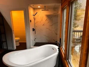 Freestanding white tub, marble tile shower, and updated bathroom fixtures in renovated master bath