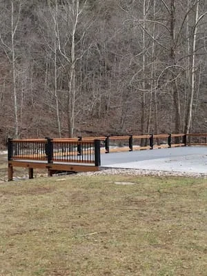 Dark composite deck with metal railings overlooking wooded area