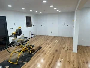 Commercial interior with drywall, recessed lights, hardwood flooring, and construction equipment