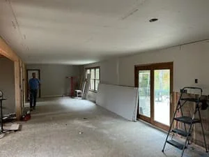 Open interior room with new drywall installation, French doors, and construction equipment