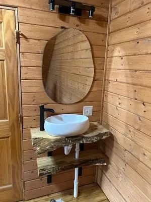 Live-edge wood vanity with vessel sink and circular mirror in shiplap wood bathroom