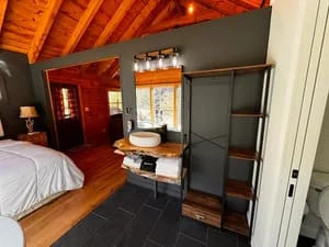 Master bedroom with exposed wood beams, custom built-in shelving, dark flooring, and updated lighting