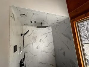 White marble tile shower enclosure with recessed lights and dual showerheads