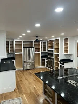Kitchen with white and dark cabinetry, black granite counters, stainless steel appliances, and recessed lighting