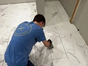 Worker measuring and marking large-format marble tile layout on floor